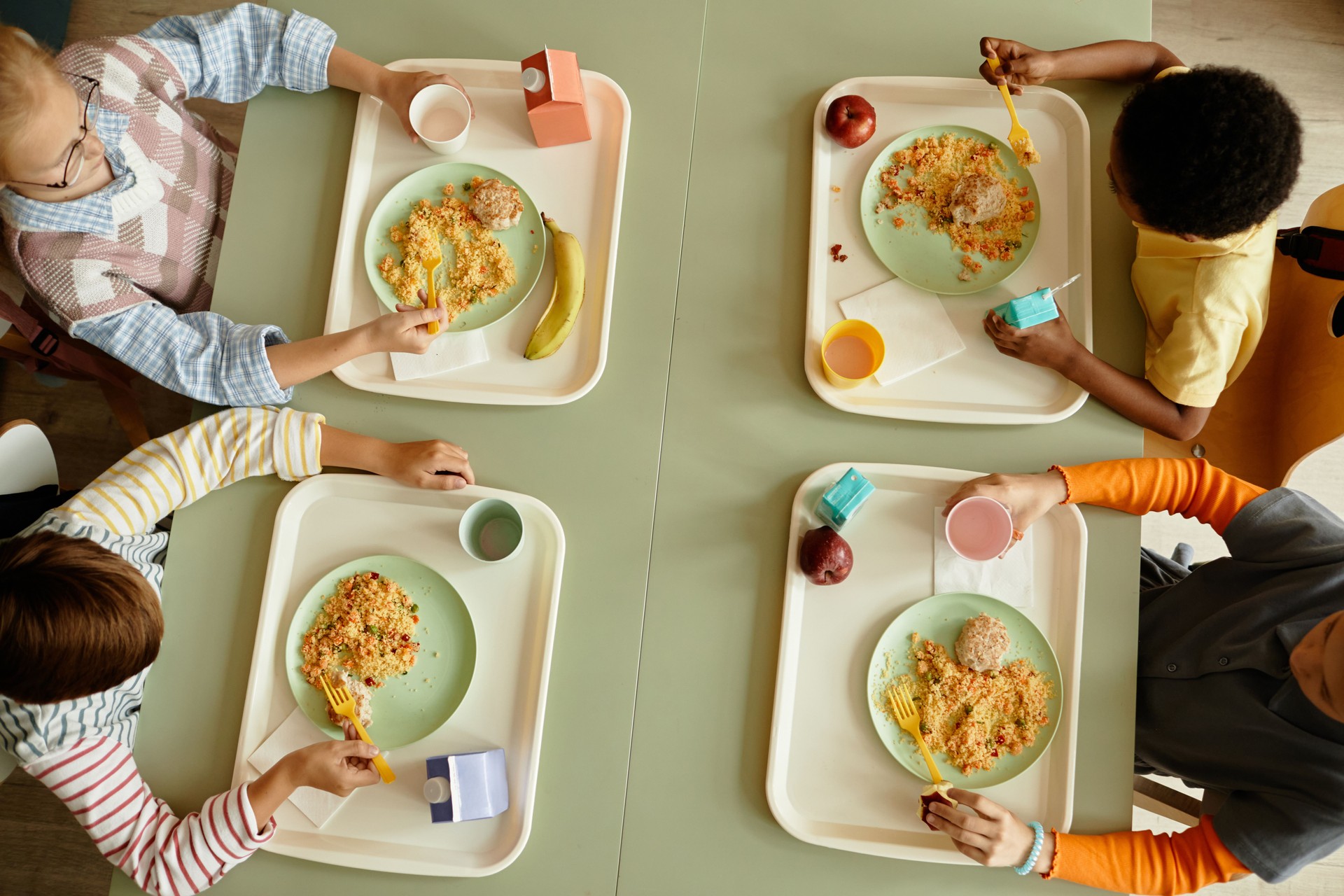 Top View of Children at Table Eating Healthy Lunch in Cafeteria